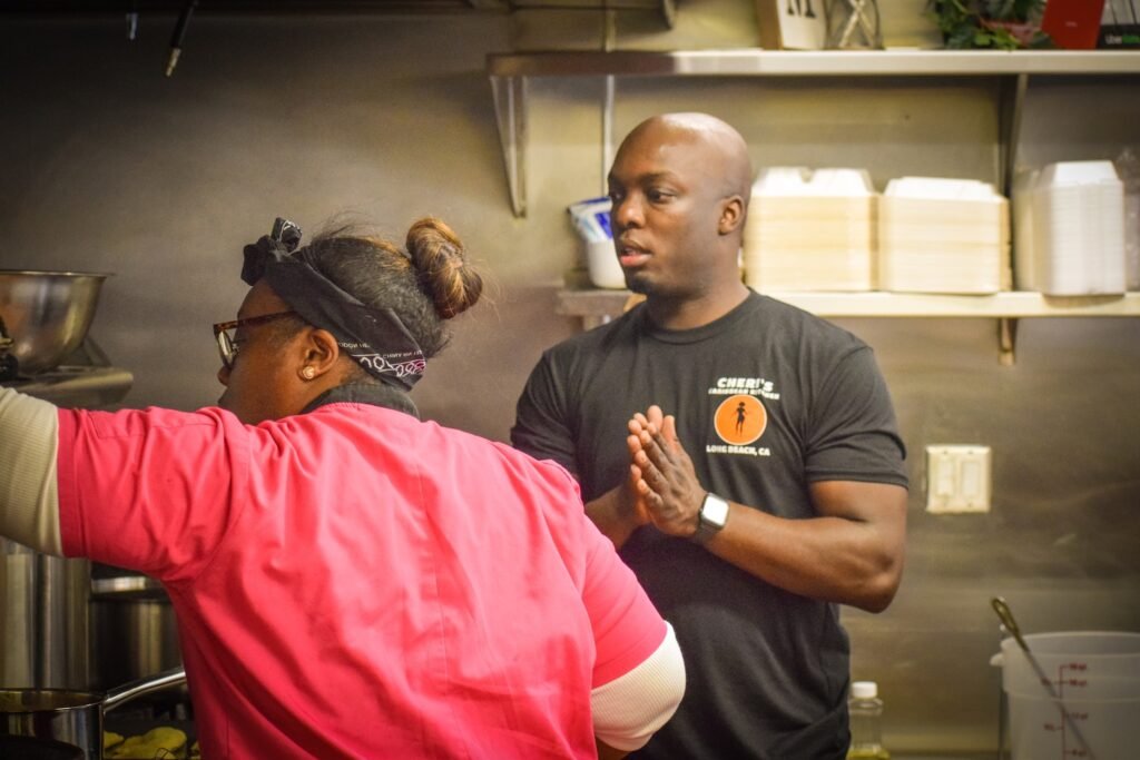 Executive Chef Tret Toussaint directs Head Chef Lakeshia Combs overseeing a pot of oxtails at Cheri's Caribbean Kitchen popup. Photo by Brian Addison.