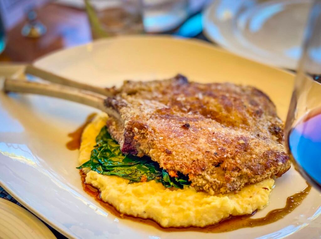 Wild boar chop butterflied, breaded, and fried atop polenta and greens from Michael's on Naples. Photo by Brian Addison.